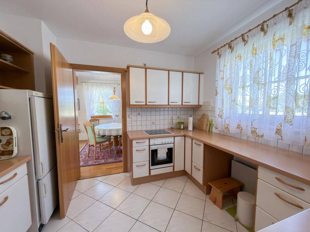 Funktionale Küche mit weißen Schränken, Holztheke und Blick in den Essbereich.