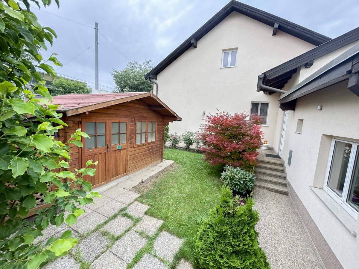 Gartenbereich mit Rasen, Sträuchern und einem praktischen Holzschuppen.