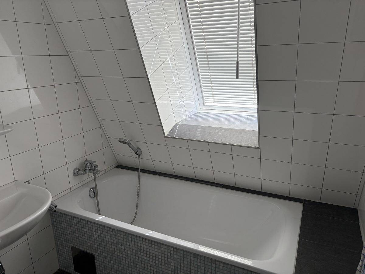Badezimmer mit Badewanne, Waschbecken, Dachschräge und Dachfenster für natürliches Licht.