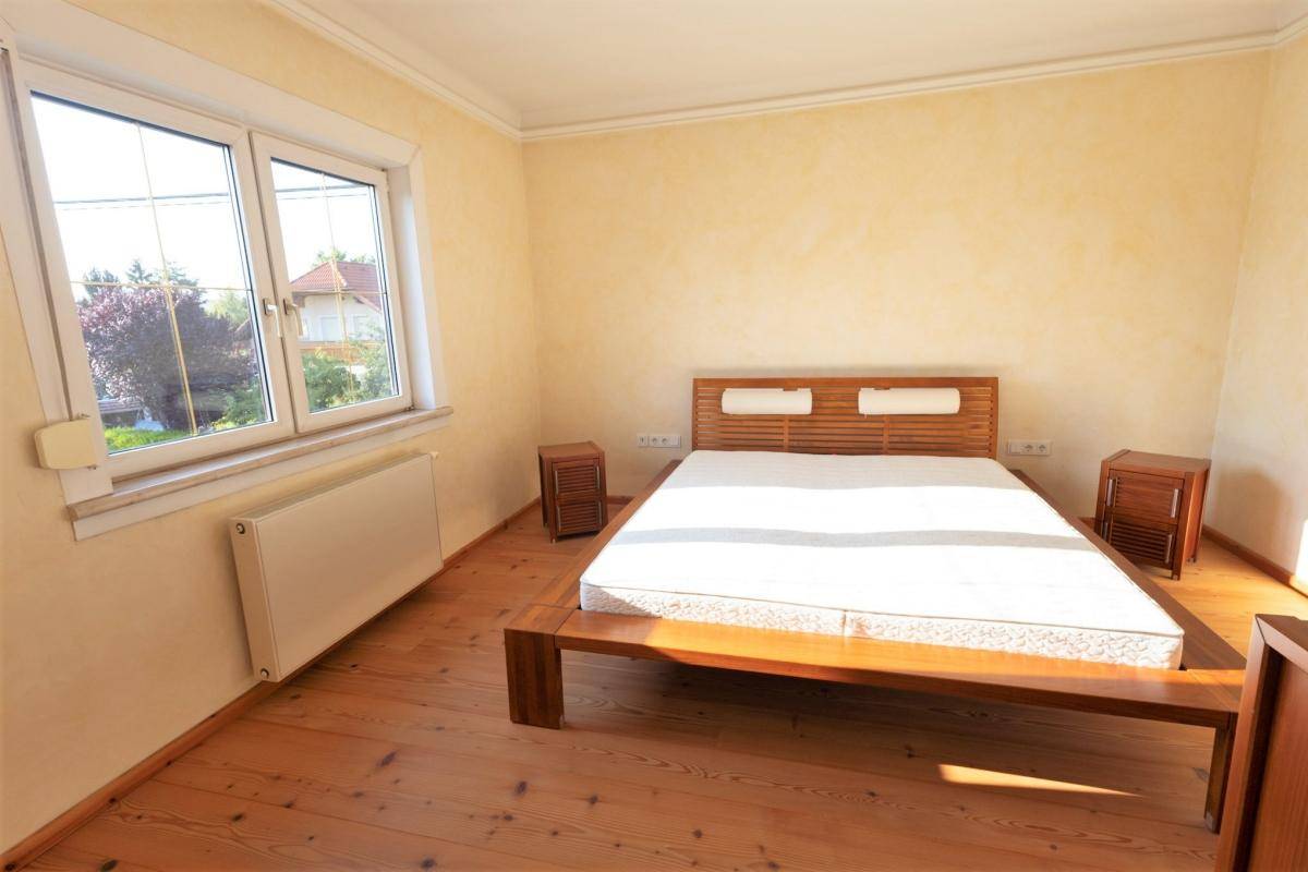 Schlafzimmer mit Holzbett, Dielenboden und großem Fenster für viel Helligkeit.