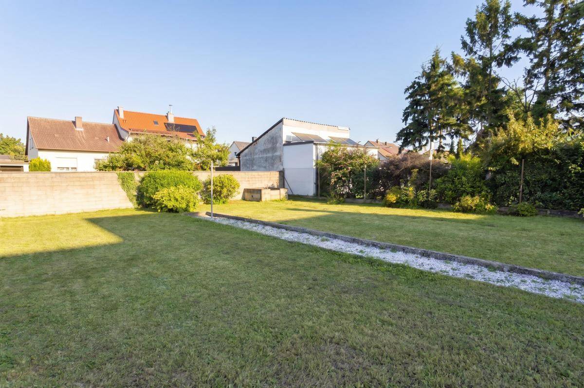 Gepflegter Gartenbereich mit Rasenfläche und umgebender Bepflanzung.