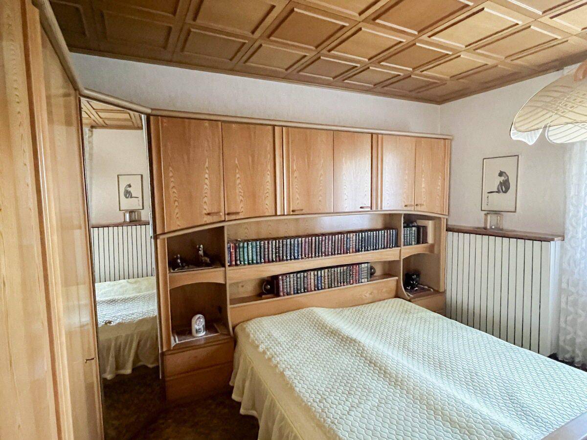 Schlafzimmer mit integriertem Bett und Schränken, Holzdecke und Teppichboden.