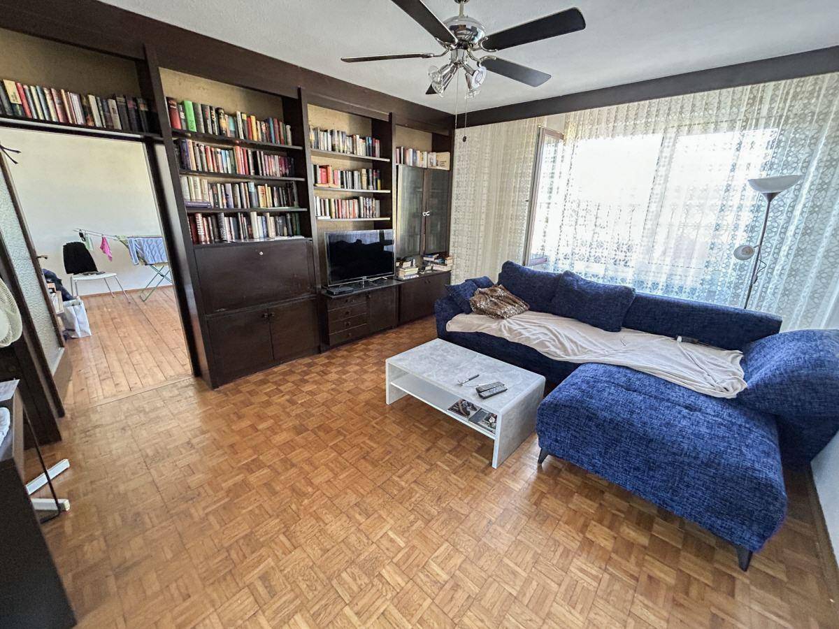 Gemütliches Wohnzimmer mit Parkettboden, großem Sofa und Bücherregalwand.