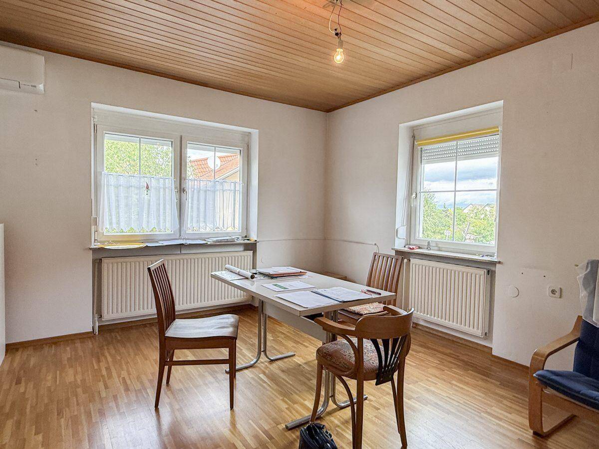 Helles Zimmer mit Holzboden, Holzdecke, Tisch und Stühlen, ideal als Büro.