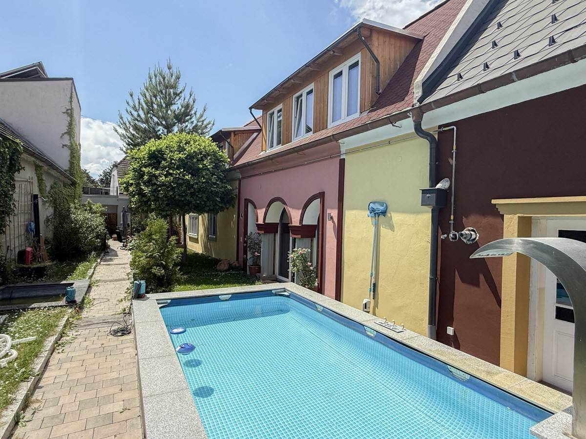Außenansicht des Gebäudes mit kleinem Pool, Rasenfläche und farbenfrohen Fassaden.