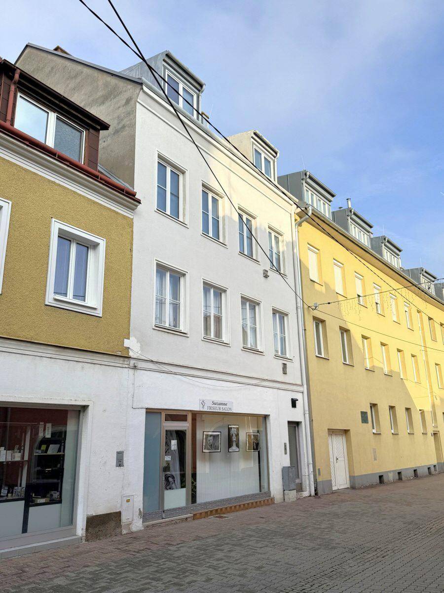 Eine Reihe von Gebäuden entlang einer Straße mit einem weißen Haus in der Mitte und einem blauen Himmel.