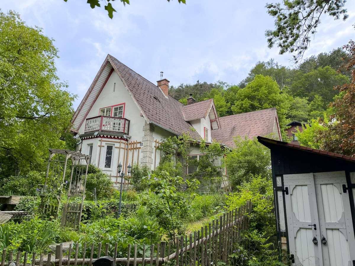 Historisches Haus mit Garten und einem kleinen, rustikalen Schuppen.