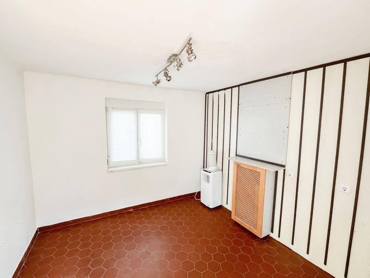 Raum mit roten sechseckigen Fliesen, kleinem Fenster und Wandverkleidung.