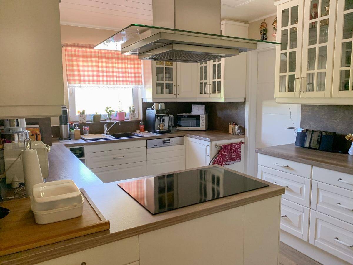 Helle Küche mit weißen Schränken, Holz-Arbeitsplatten und Kochinsel mit Induktionskochfeld.