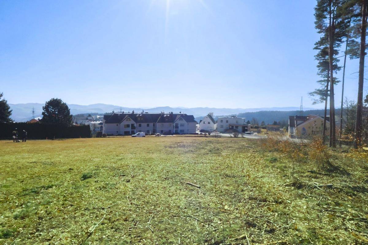 Sonniges, offenes Grundstück mit weitem Blick auf die umliegende Wohnbebauung und die entfernten Berge.