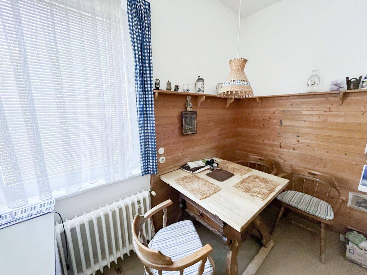 Rustikale Wohnküche mit Holztäfelung, Esstisch und einem Fenster mit karierten Vorhängen.