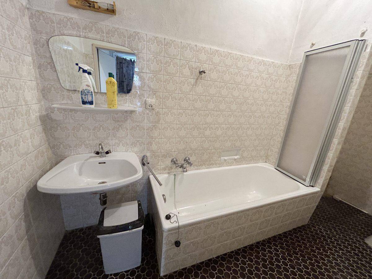 Badezimmer mit Badewanne, Waschbecken und gemusterten Fliesen an den Wänden.