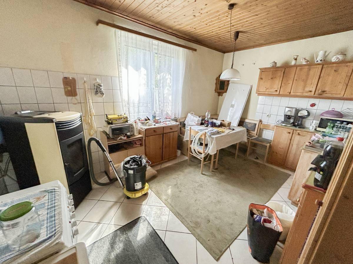Rustikale Küche mit Holzschränken, gefliesten Wänden und einem Kaminofen, der Wärme spendet.