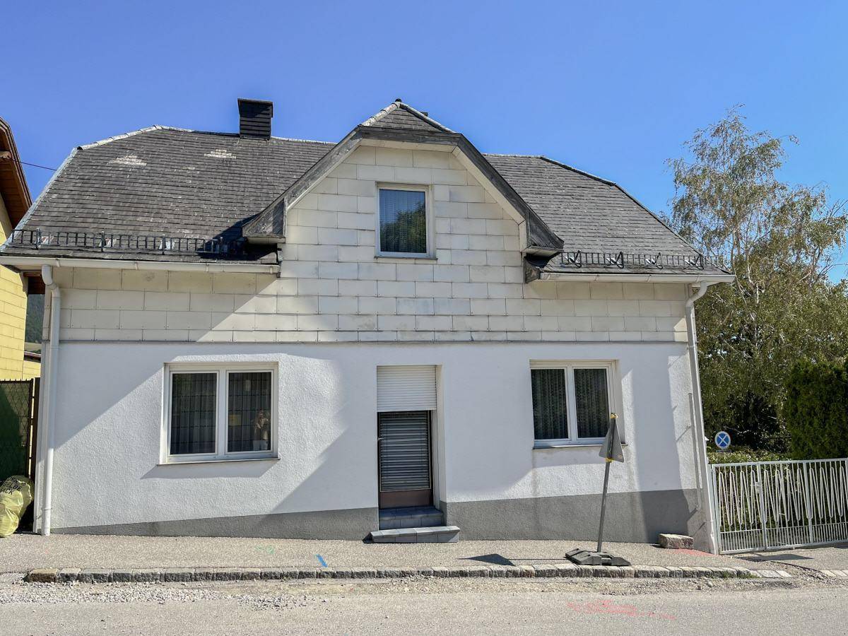 Vorderansicht des Hauses von der Straße aus mit Satteldach und Rollläden.