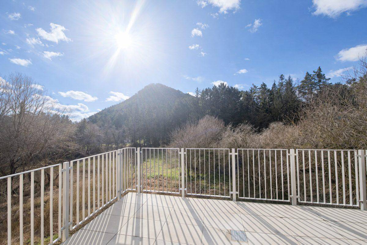Sonniger Balkon mit Fliesenboden und weitem Blick auf bewaldete Hügel und Berge.