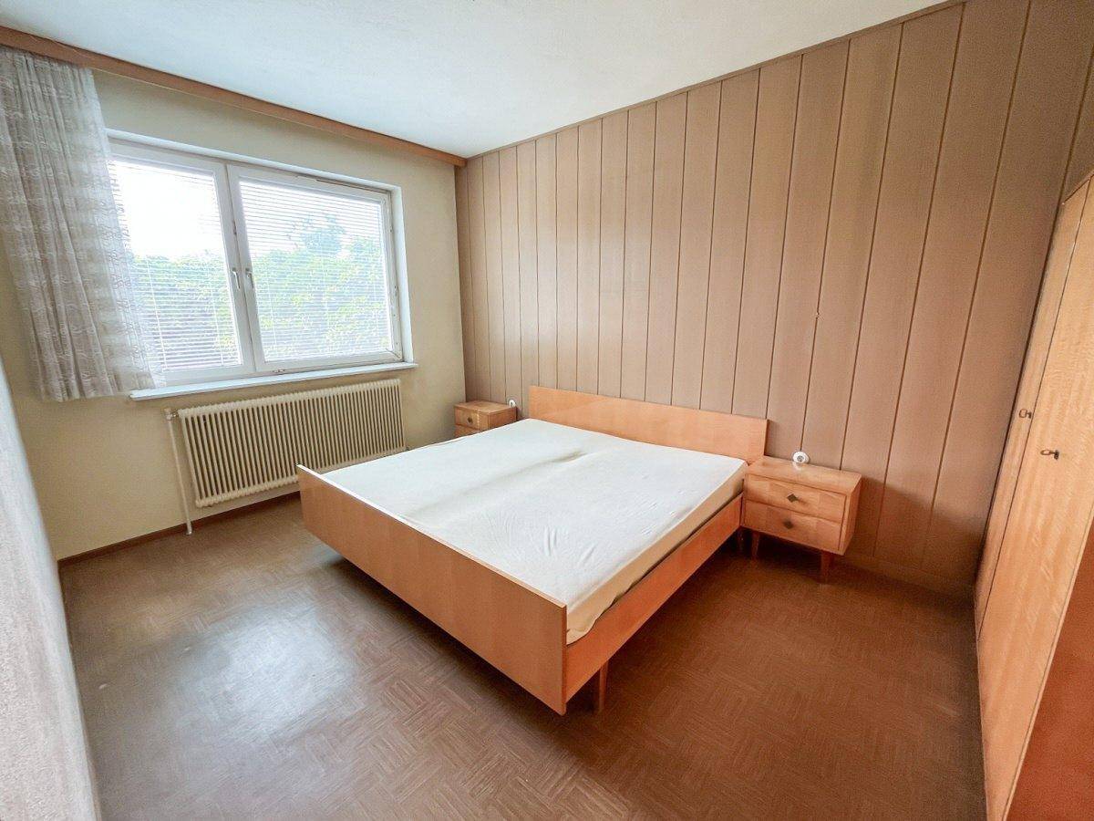 Schlafzimmer mit Holzvertäfelung, Doppelbett und großem Fenster.