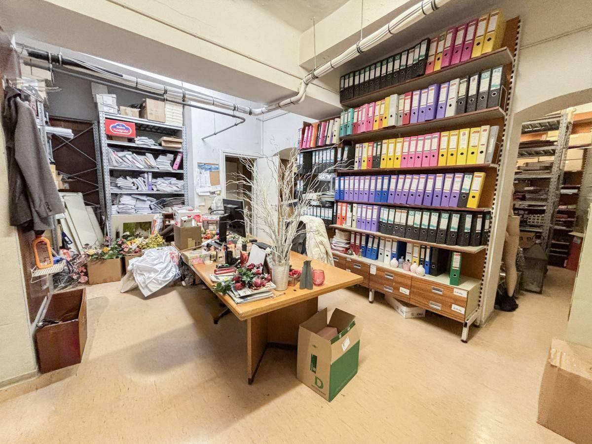 Büro- und Lagerraum mit einem Schreibtisch, vielen Aktenordnern in Regalen und Dokumenten.