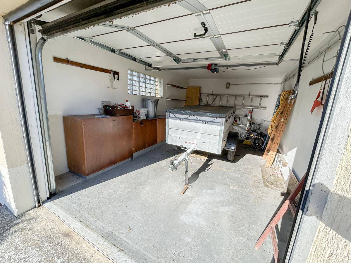 Geräumige Garage mit Betonboden und Stauraum für Fahrzeuge und Geräte.