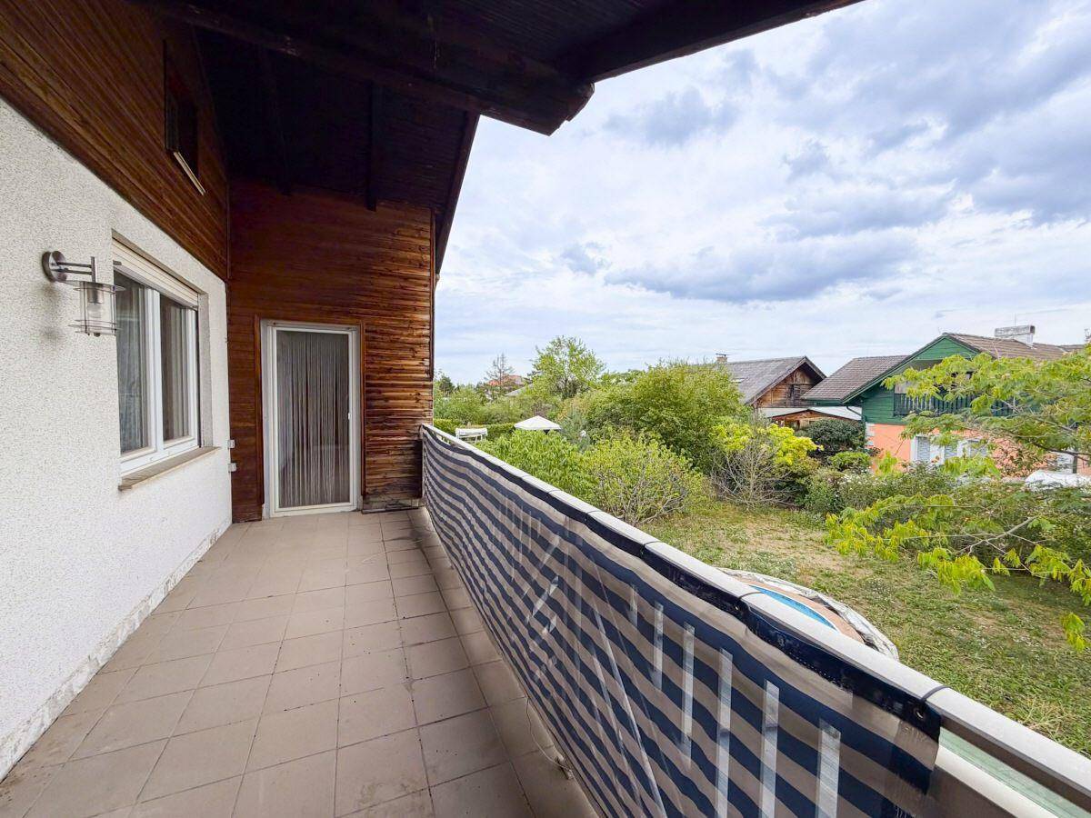Balkon mit Fliesenboden, Holzverkleidung und weitem Blick ins Grüne.