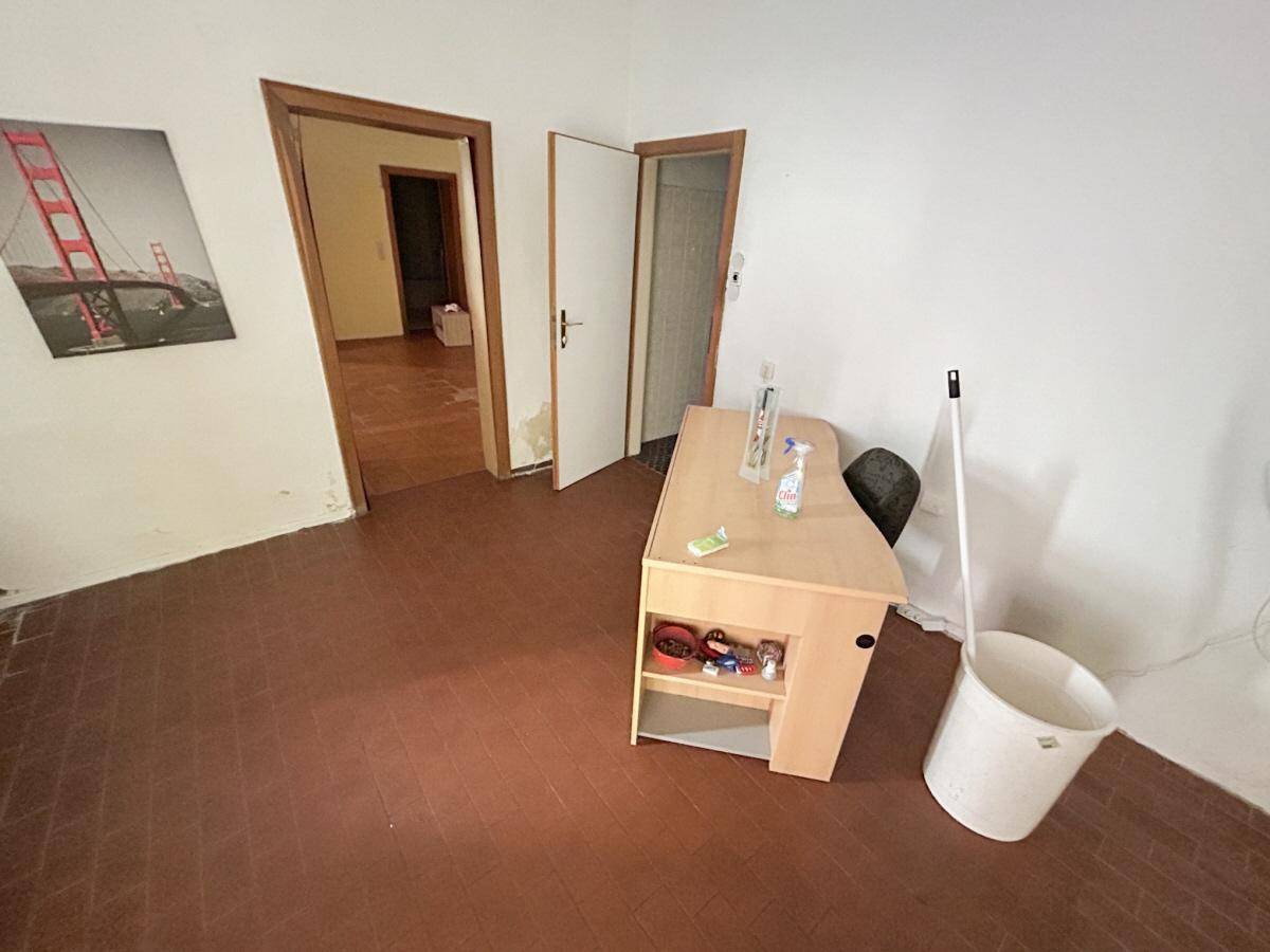 Leerer Raum mit Terrakotta-Fliesenboden und mehreren Türen zu angrenzenden Zimmern.