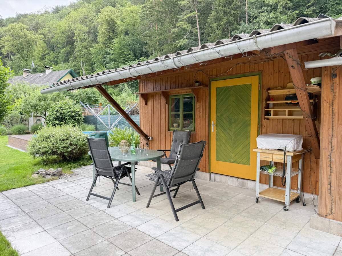 Gemütliche Terrasse mit Sitzgelegenheiten und Grillbereich, angrenzend an ein Holzgebäude.