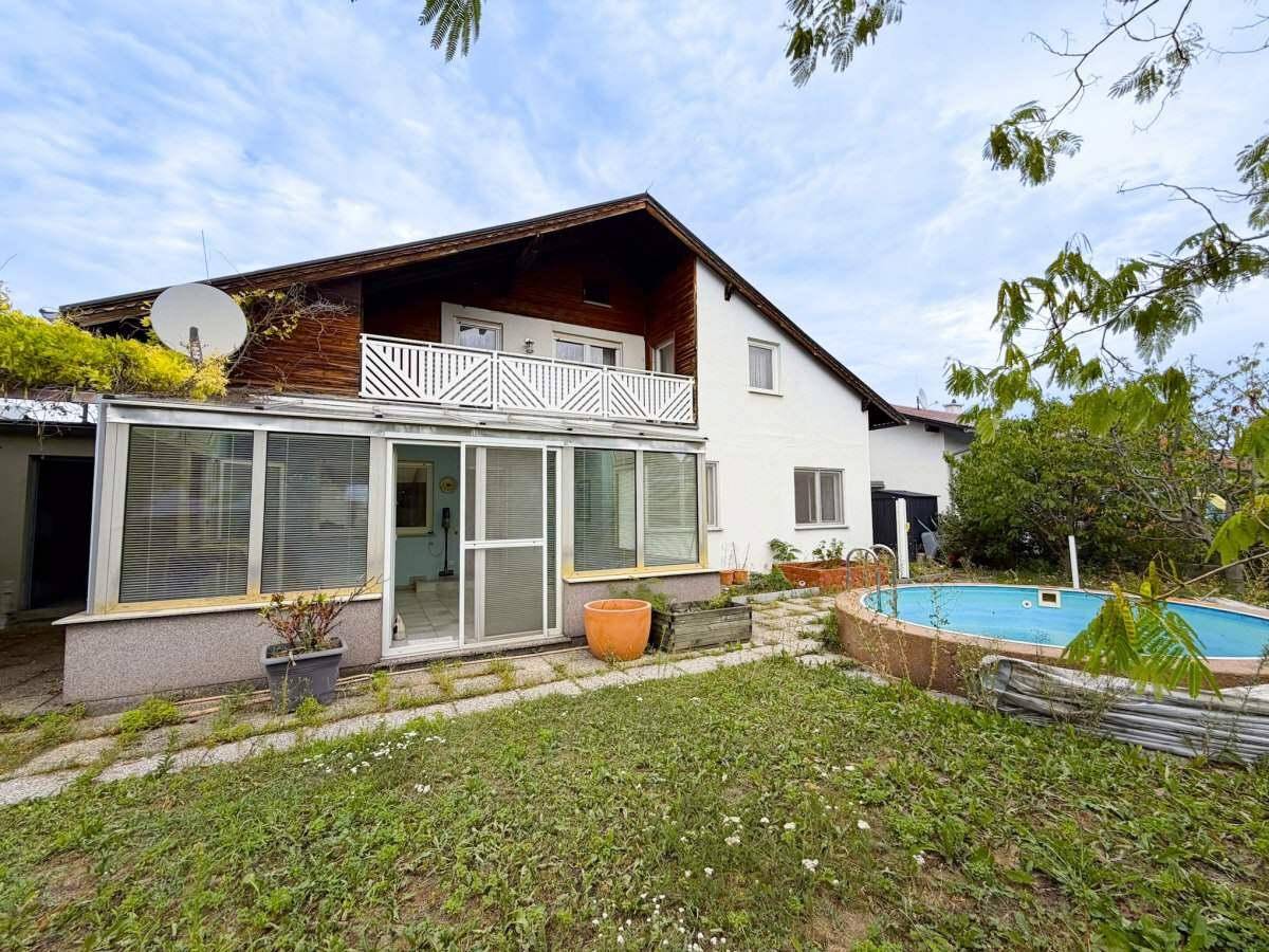 Rückansicht des Hauses mit Wintergarten, Garten und eingelassenem Pool.