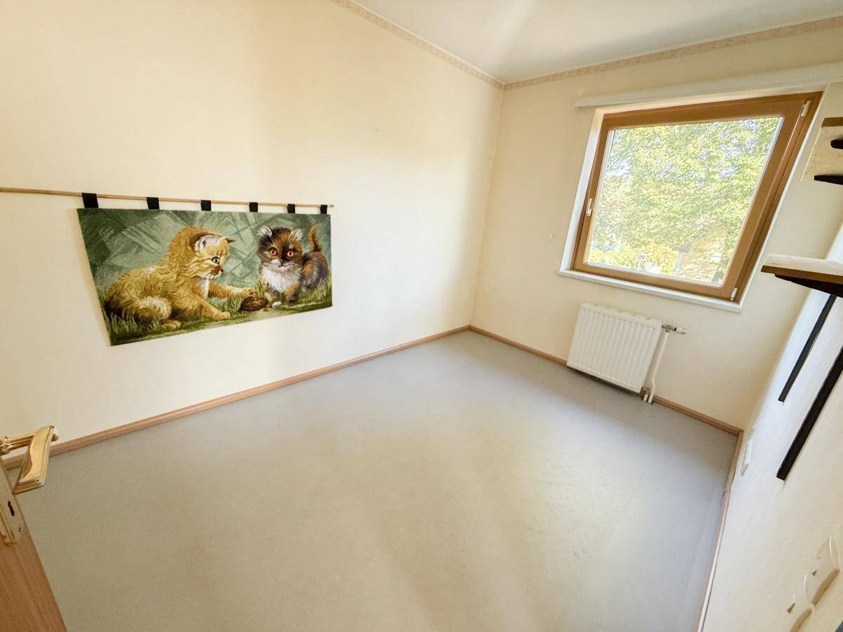 Helles Kinderzimmer oder Gästezimmer mit Fenster und Teppichboden, neutral gestaltet.