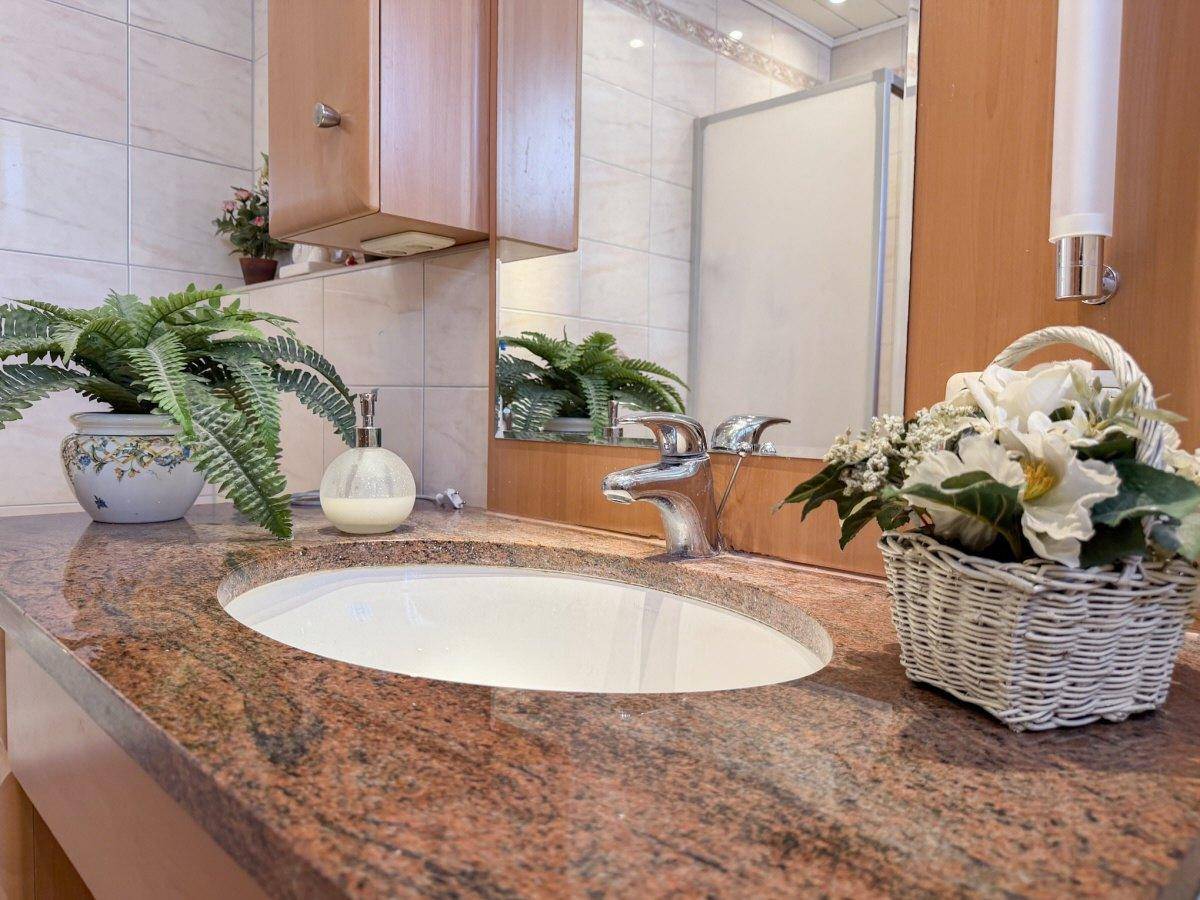 Detailaufnahme des Waschtischs im Badezimmer mit Granitplatte und integriertem Waschbecken.