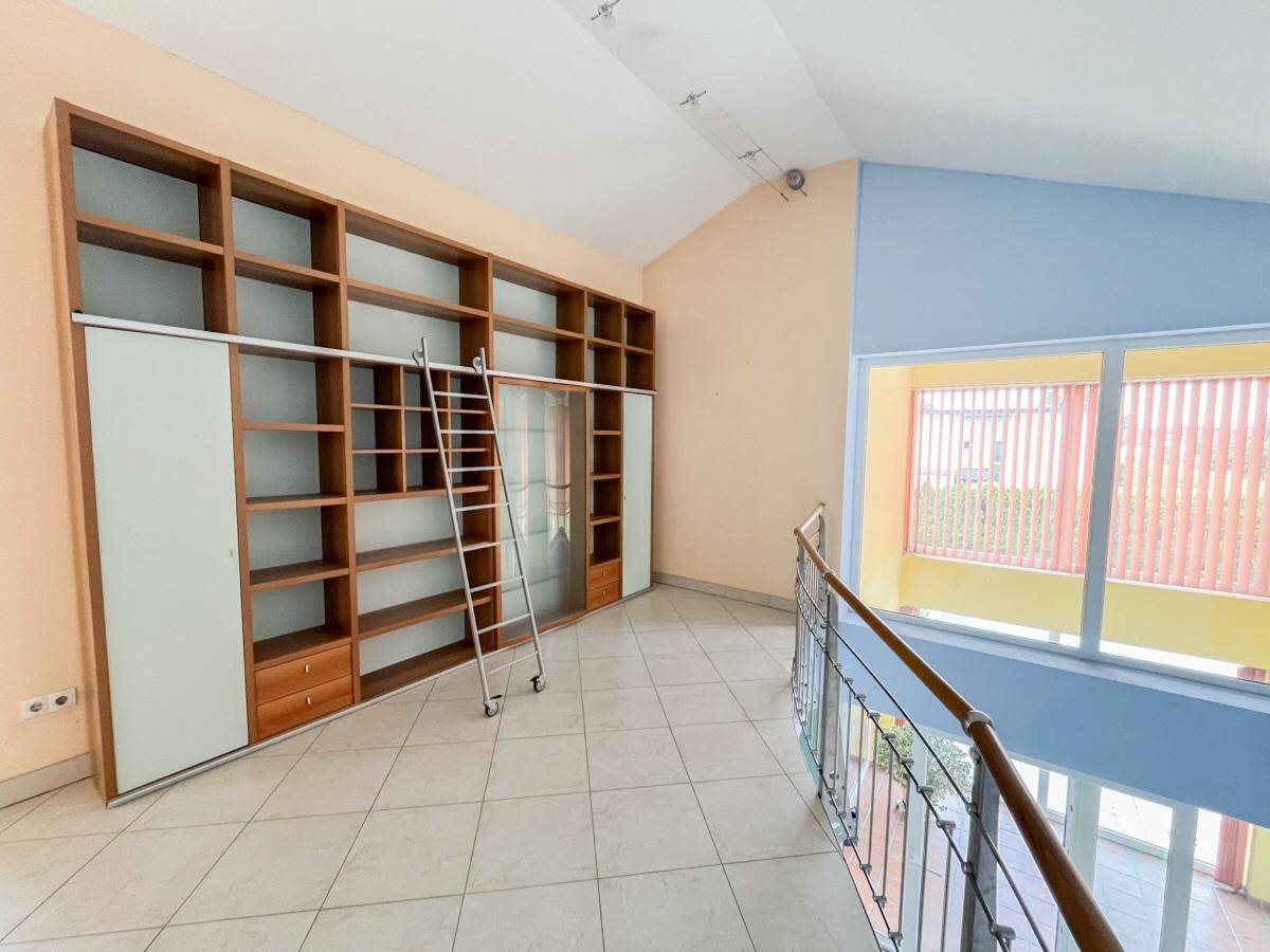 Helle Galerie mit großer Bücherwand und Blick auf den offenen Wohnbereich im Erdgeschoss.