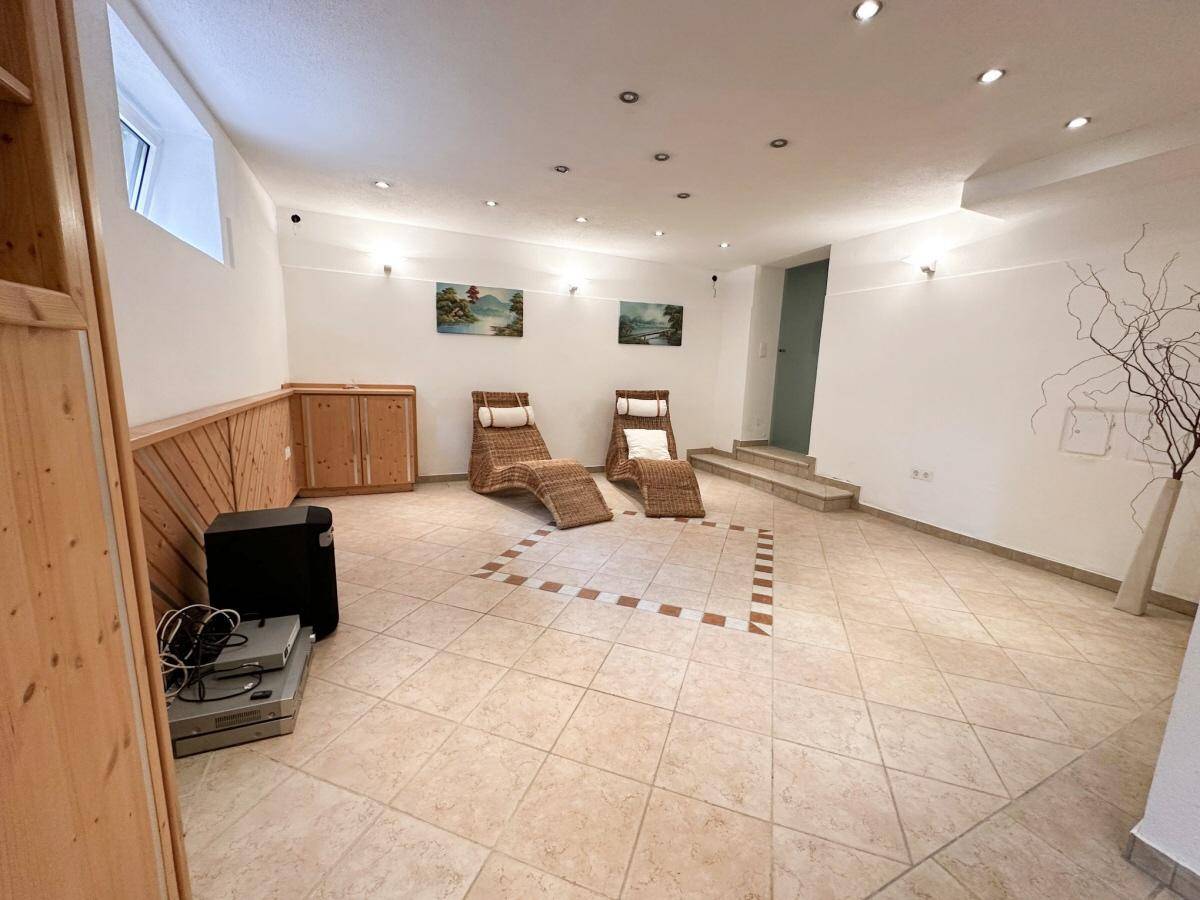 Geräumiger Wellnessbereich im Keller mit Fliesenboden und Liegestühlen zum Entspannen.
