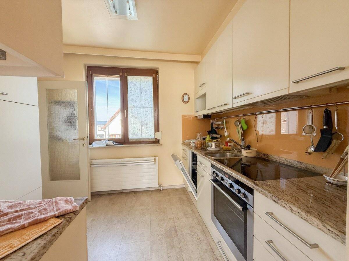 Helle Küche mit Granitarbeitsplatten, modernen Geräten und einem Fenster mit Ausblick.