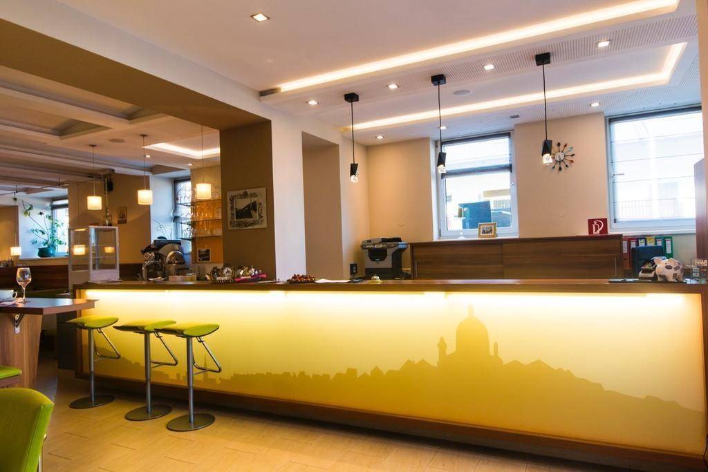 Moderne Bar mit beleuchteter Theke, Barhockern und Blick auf die Stadt durch die Fenster.