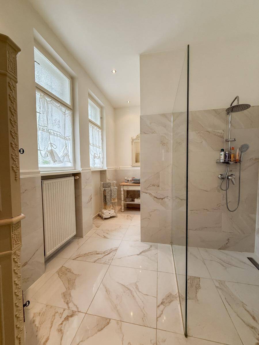 Modernes Badezimmer mit großformatigen Marmorfliesen und einer begehbaren Dusche.