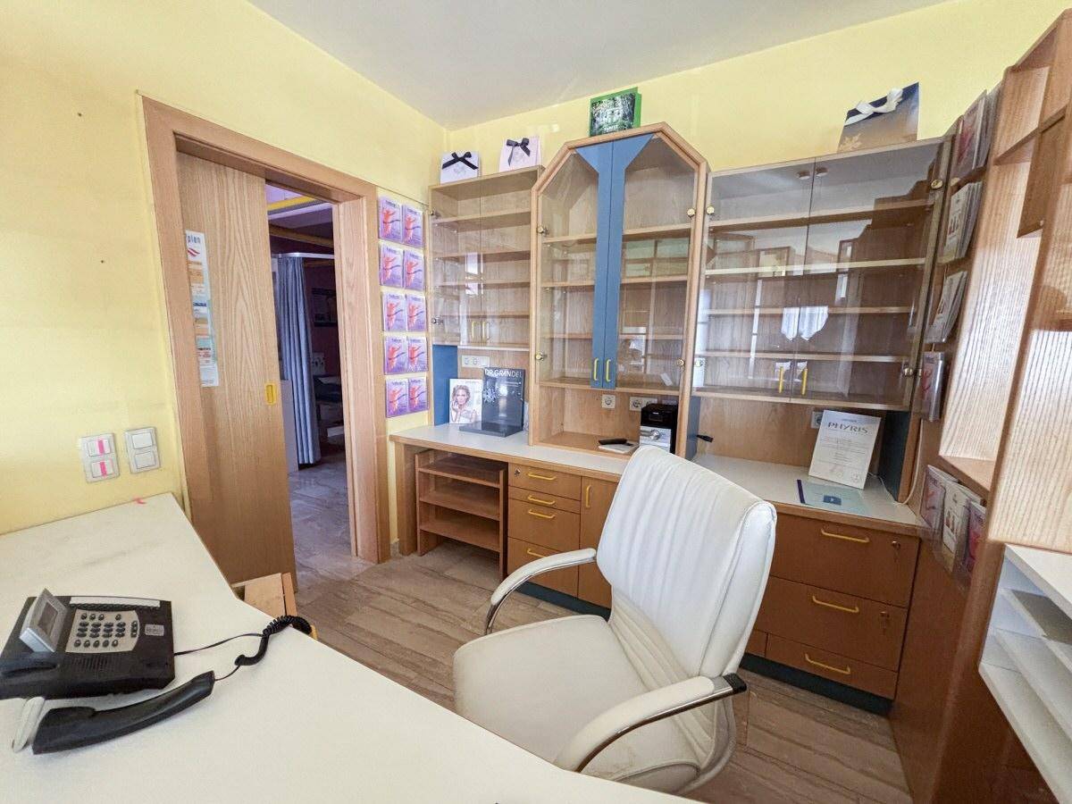Büroraum mit Holzmöbeln, Schreibtisch und Bürostuhl, durch eine Schiebetür zugänglich.
