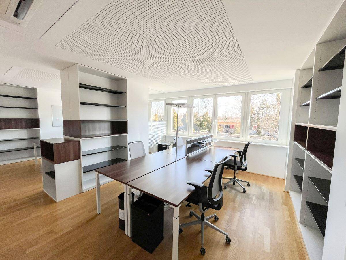 Geräumiges Büro mit mehreren Schreibtischen, ergonomischen Stühlen und viel Tageslicht, fördert die Produktivität.