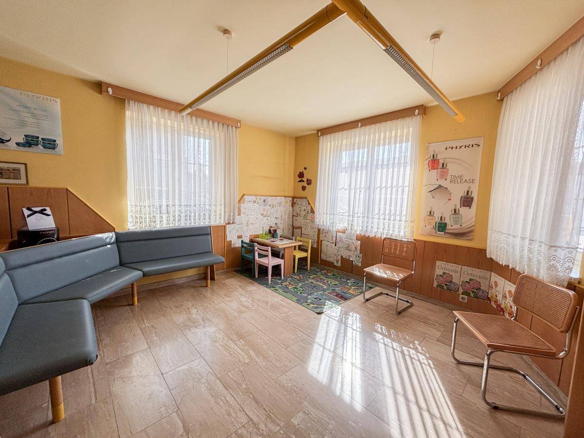 Wartezimmer mit bequemen Sitzbänken, einem Kinderspielbereich und großen Fenstern für viel Tageslicht.