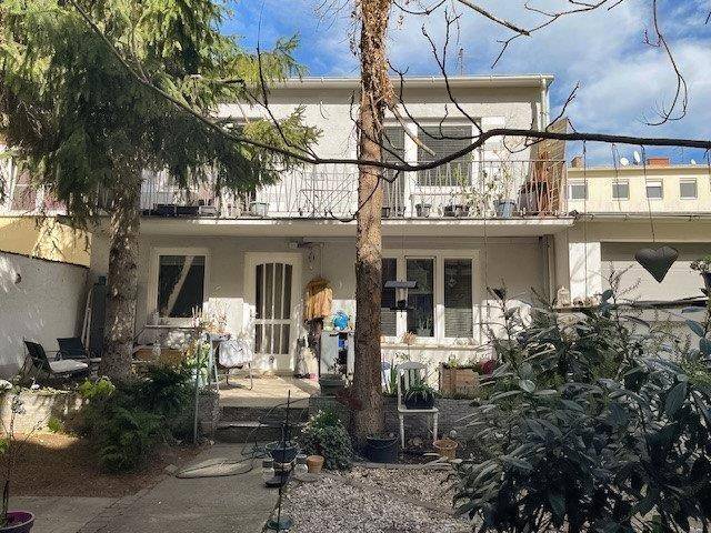 Ein kleiner, gepflegter Gartenbereich hinter dem Haus mit Sitzgelegenheiten und verschiedenen Pflanzen.
