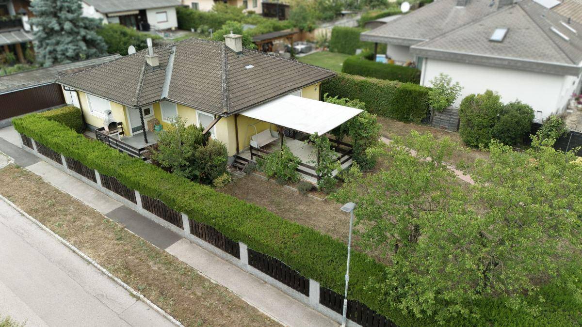 Luftaufnahme des Einfamilienhauses mit großem Garten und Hecke, umgeben von Nachbarhäusern.