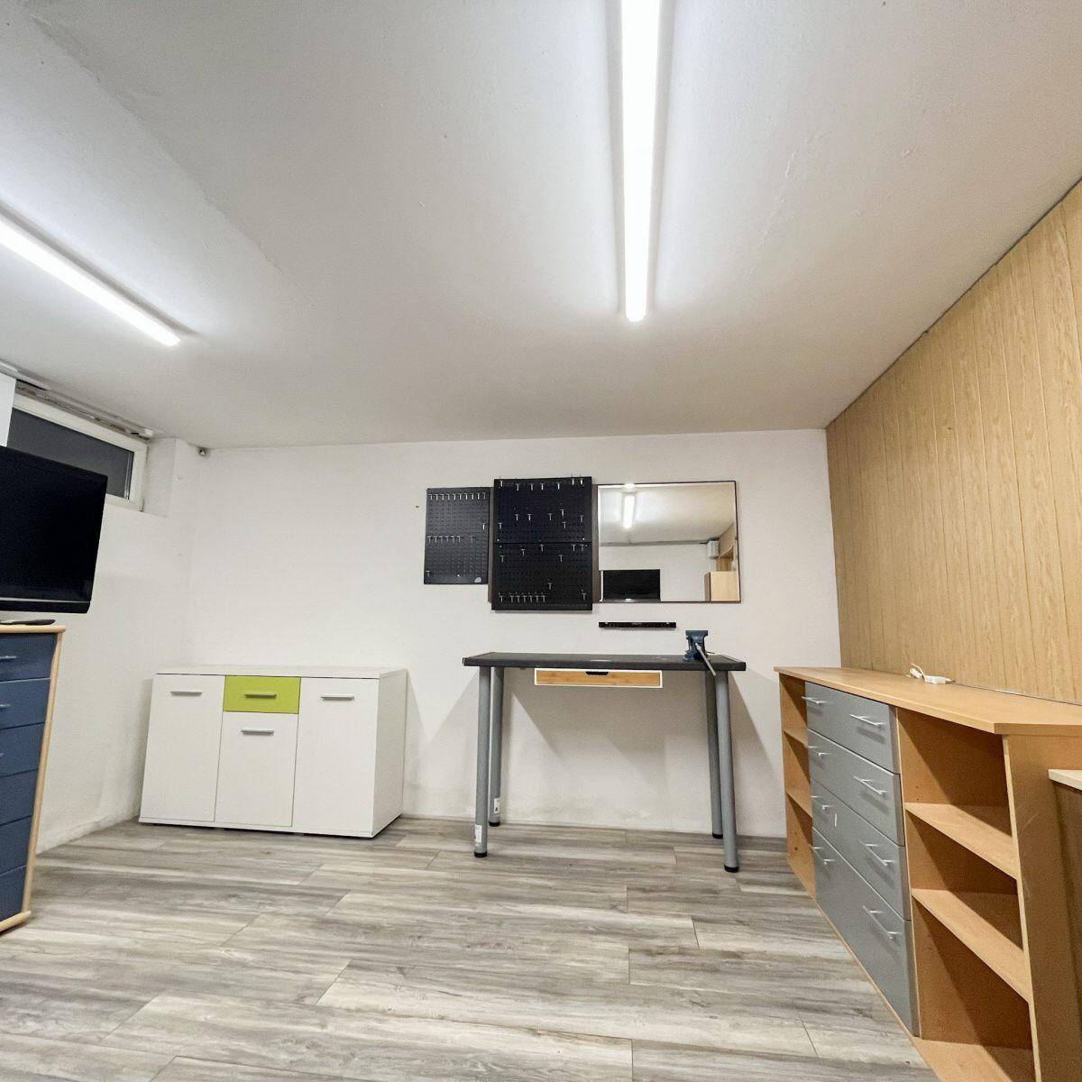Heller Kellerraum mit Laminatboden, Schränken und Arbeitsbereich, vielseitig nutzbar.