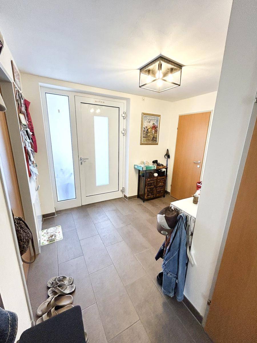 Heller Eingangsbereich mit Fliesenboden und Garderobe, der zu den Wohnräumen führt.