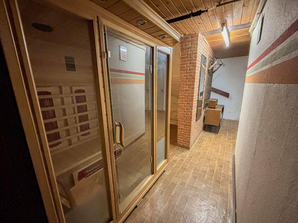 Wellnessbereich im Keller mit einer Holzsauna und rustikalen Ziegelwänden.
