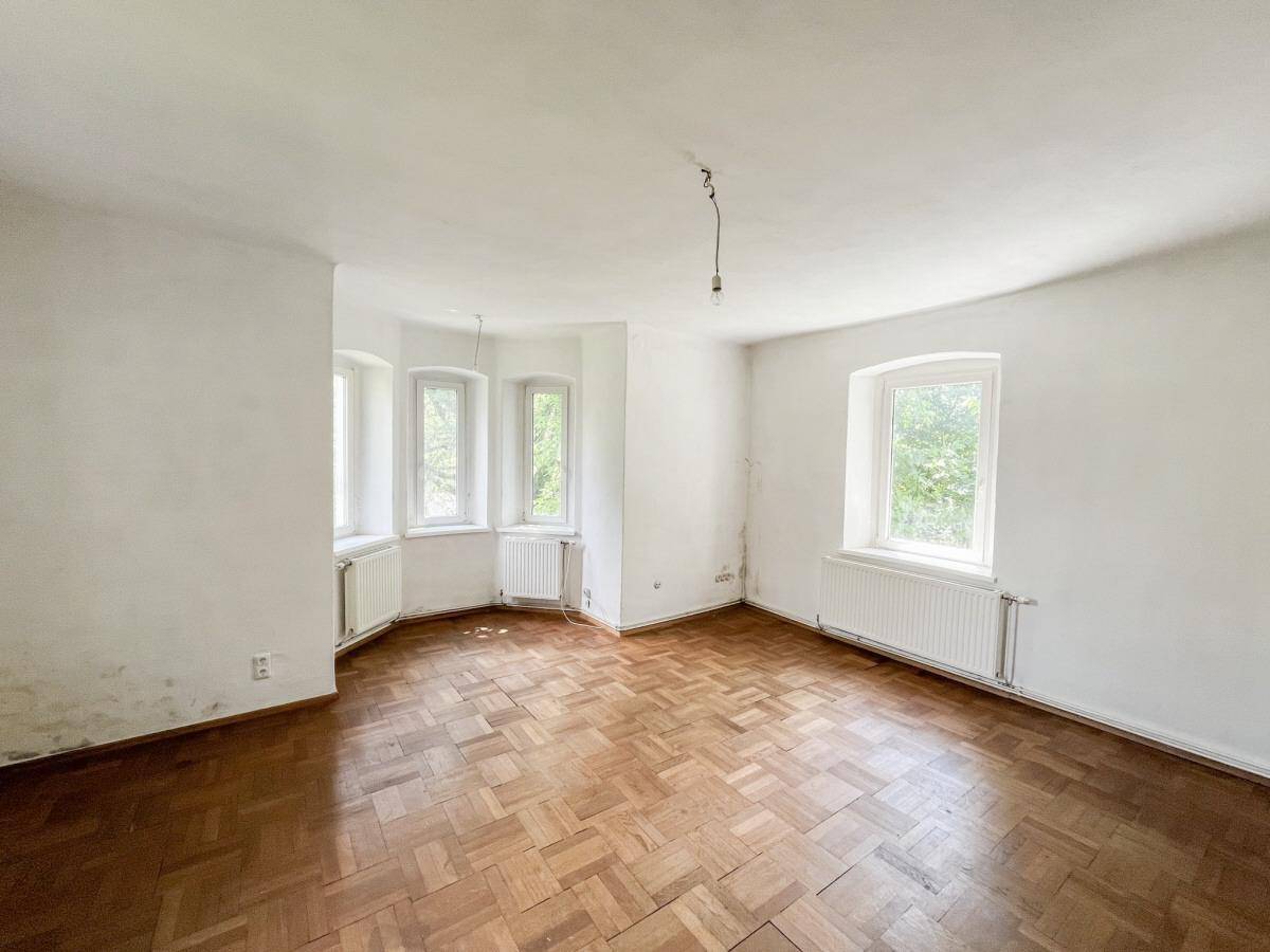 Geräumiges Zimmer mit Fischgrätparkett, Erkerfenstern und viel Tageslicht.