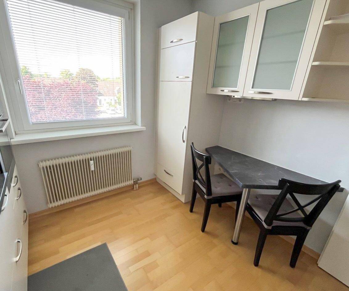 Essbereich in der Küche mit kleinem Tisch und Stühlen neben dem Fenster.