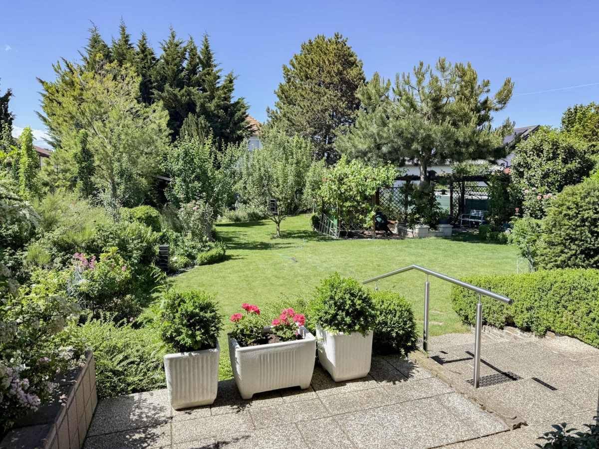 Großer, gepflegter Garten mit Rasenfläche, Bäumen und Sträuchern.