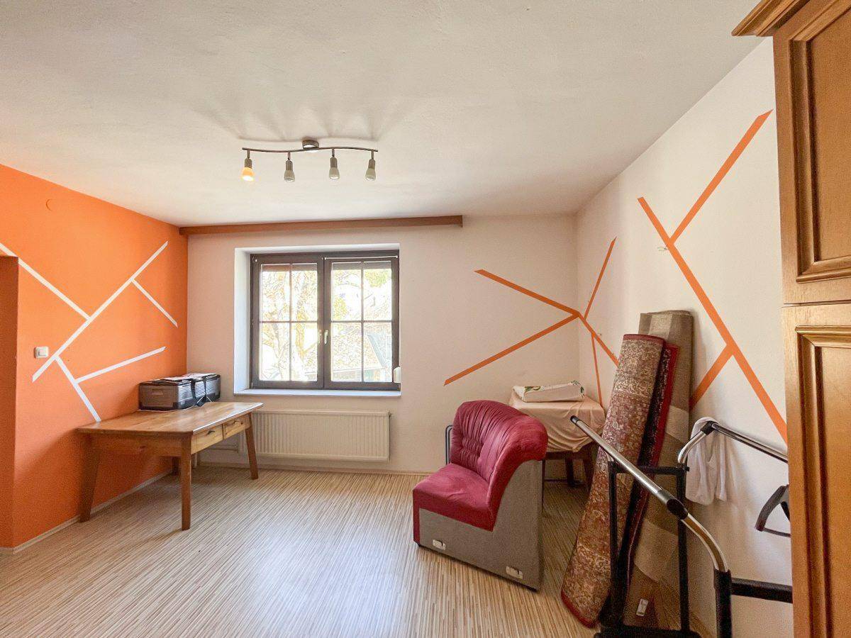 Heller Raum mit Laminatboden und auffälliger orangefarbener Wandgestaltung.