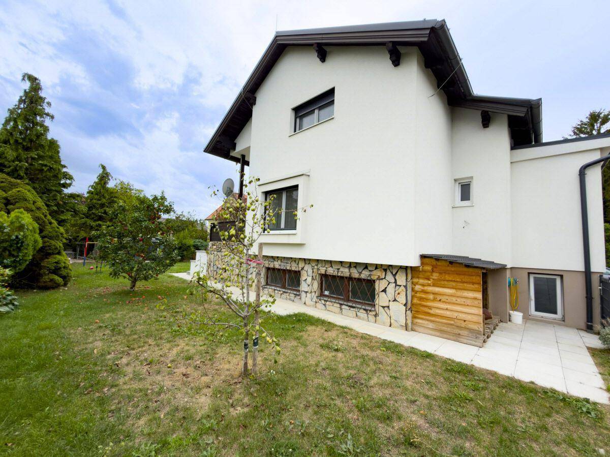 Seitenansicht des Hauses mit Steinfassade und gepflegtem Gartenbereich.