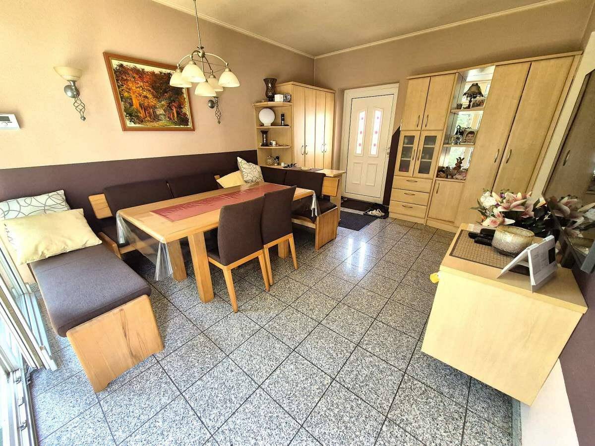Gemütlicher Essbereich mit eingebauter Sitzbank, Holztisch und gefliestem Boden.