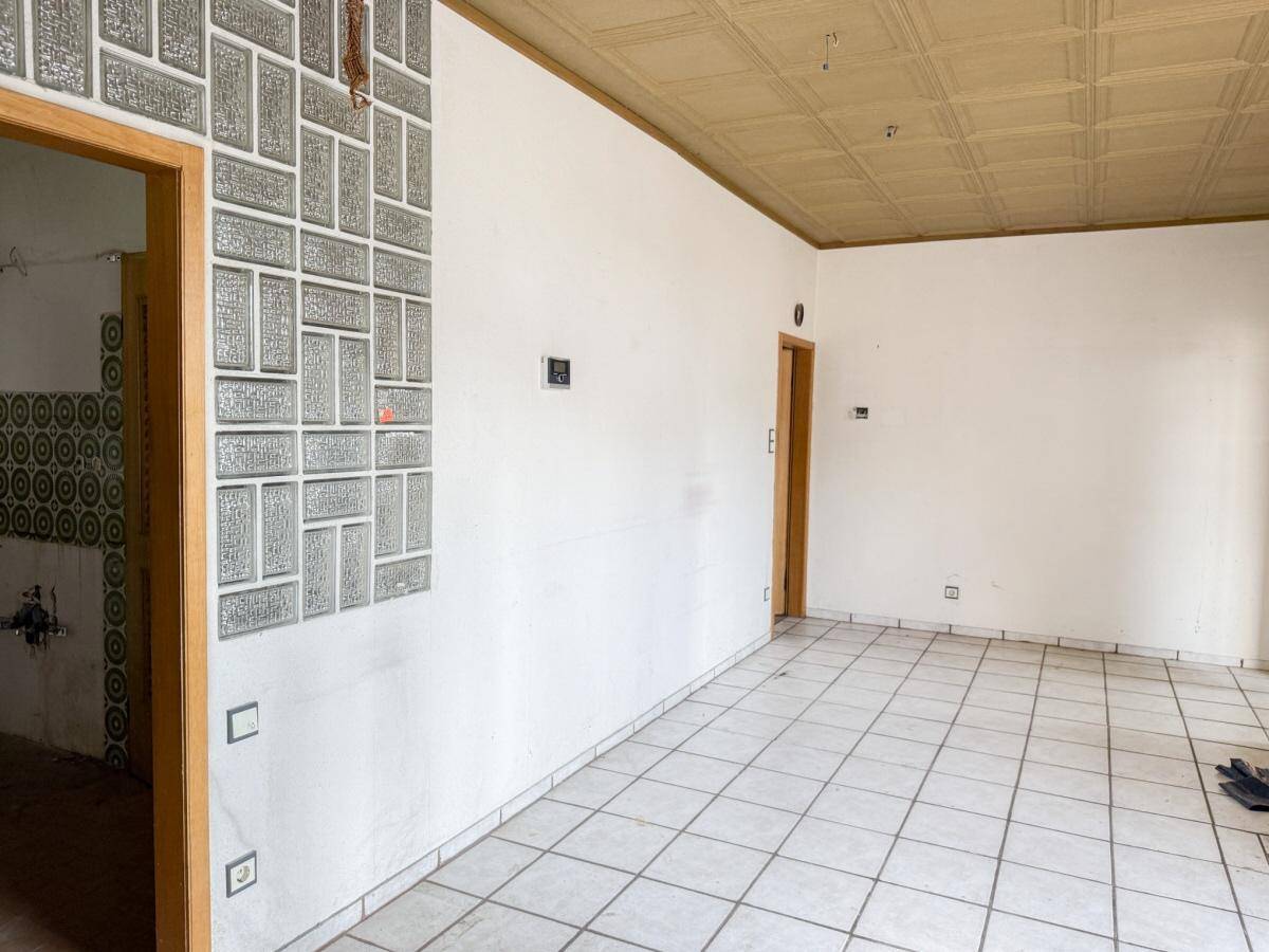 Großer, leerer Raum mit Fliesenboden und Glasbausteinwand, bereit zur Gestaltung.