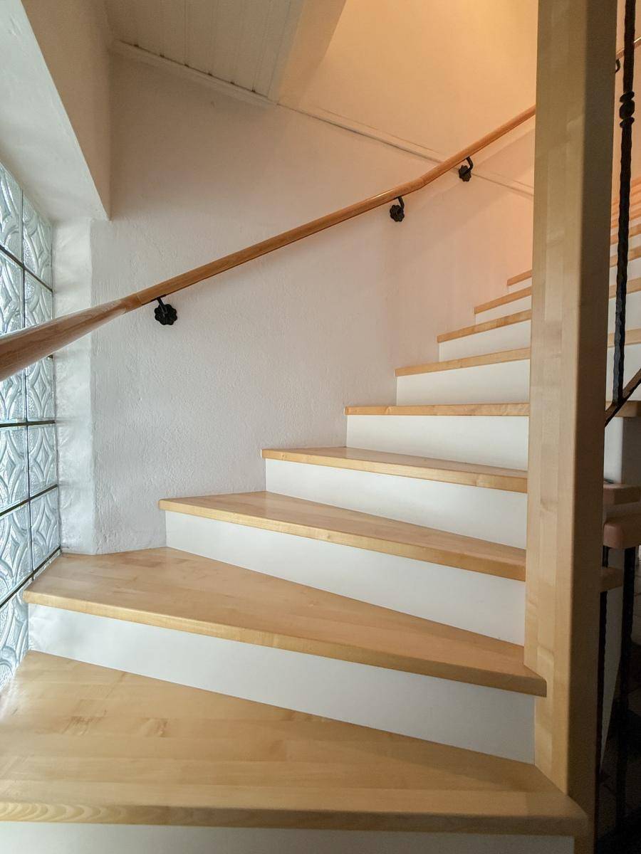 Helle Holztreppe mit Holzgeländer und dekorativem Glasbausteinfenster.