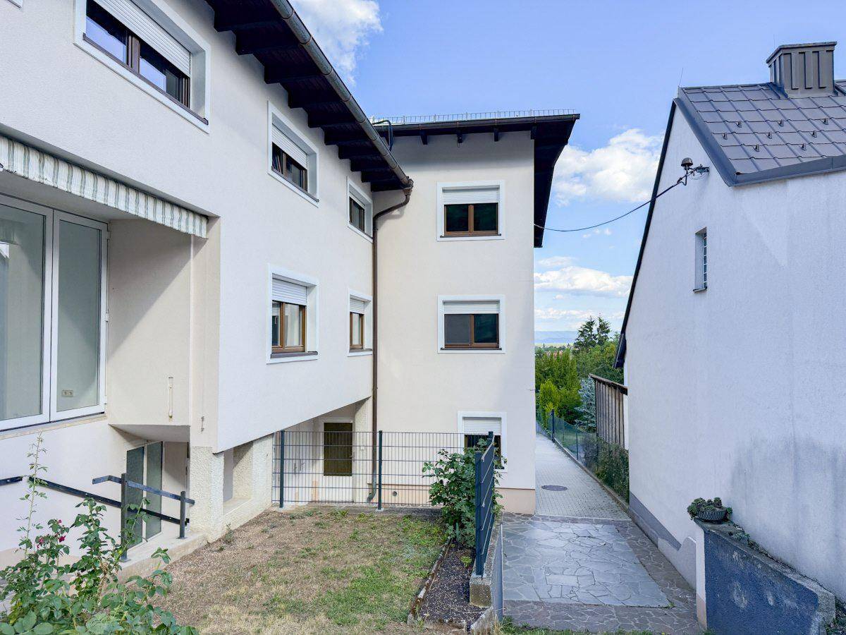 Seitenansicht des Hauses mit Fenstern, Rollläden und einem kleinen Gartenbereich.